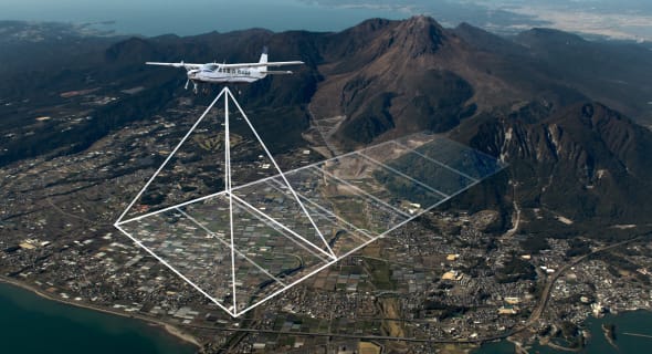 A plane captures overlapping aerial images of a landscape — the raw data used to reconstruct the terrain in 3D through photogrammetry.